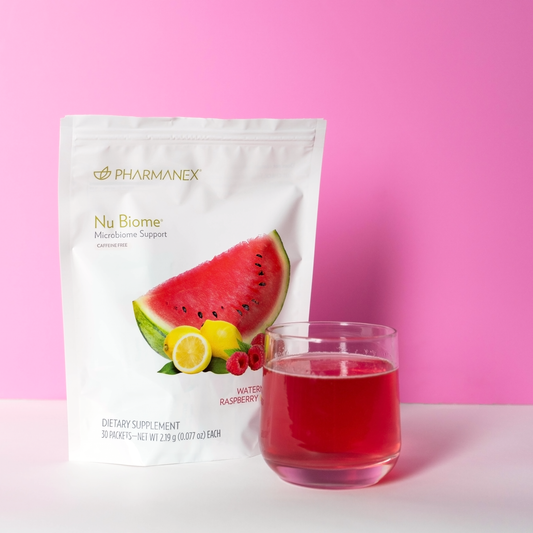 Nu Biome raspberry lemon flavor dietary supplement with a pink drink in a clear glass, set against a bright pink background.